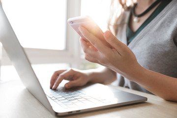 Young women working on her laptop and smart phone, Women hands using smart phone in the office.