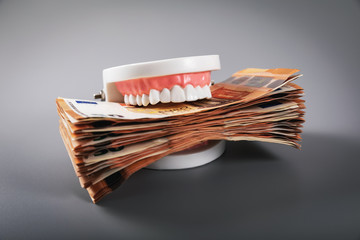 greediness concept - teeth model eating euro money bills