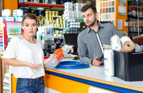 Young man seller discussing with upset female customer  in tool-ware shop