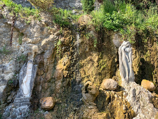 New Athos, Abkhazia. Stone sculptures and a small waterfall on the Bank of the river Psyrtskha in summer