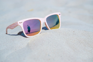Fototapeta na wymiar Young woman reflect in pink sunglasses on the beach, summer concepts