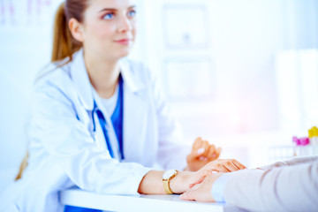 The doctor holds the patient's hand in the office. Young specialist reassures patient