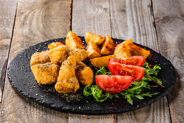Fried chicken nuggets, baked potatoes and vegetable salad