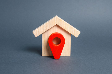 Figurine wooden house and red location pointer. The concept of the location of a building,...