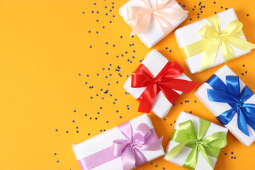 gifts and confetti on a colored background top view. Holiday giving gifts