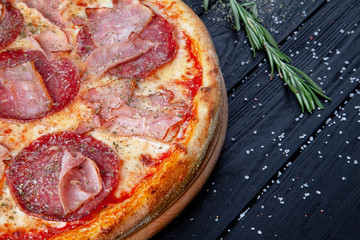 Top view pizza with salami, hot pepper chili, ham and cheese on dark wooden background. Copy sapce for design. Food background. Italian cuisine. Flat lay food