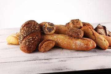 Assortment of baked bread and bread rolls on white table background