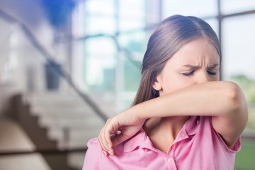 Young woman scratching her nose with elbow on background