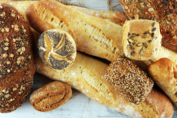 Assortment of baked bread and bread rolls on white table background