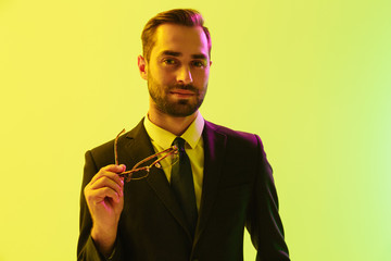 Cheery smiling happy young business man posing isolated over light green background wall with led neon lights.
