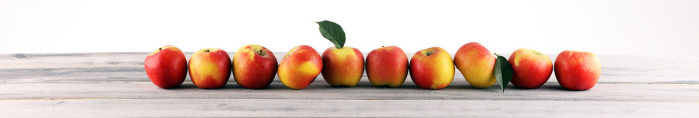 Ripe red apples with leaves on wooden background