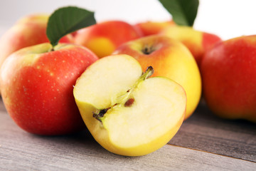 Ripe red apples with leaves on wooden background