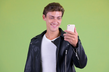 Portrait of young happy rebellious man using phone