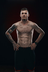 Fototapeta na wymiar Tattoo strong boxer stand in front of dark background