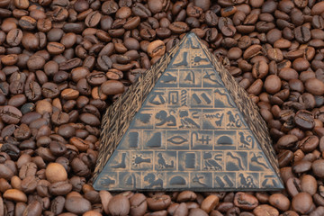 pyramid figurine lies on a background of coffee beans