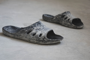 black rubber flip-flops standing on a concrete floor, the concept of repair.