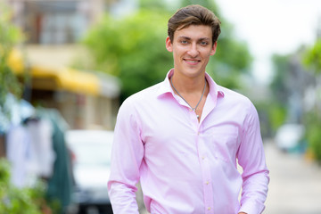 Fototapeta premium Portrait of happy young handsome businessman smiling outdoors