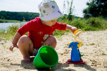 Closeup photo of a little girl.   A child plays with the sand on the beach.