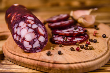Cutting board with sliced salami sausage and garlic on a wooden table