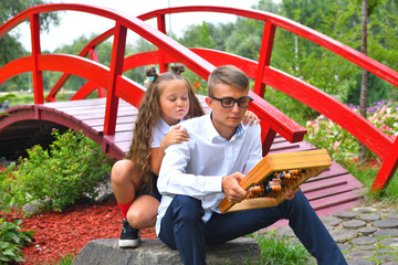Boy and first-grader girl with large abacus. Thoughtful schoolboy and schoolgirl using a maths abacus calculation