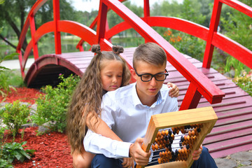 Boy and first-grader girl with large abacus. Thoughtful schoolboy and schoolgirl using a maths abacus calculation