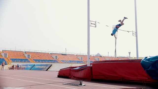 Pole vault training - an athletic man jumping over the bar
