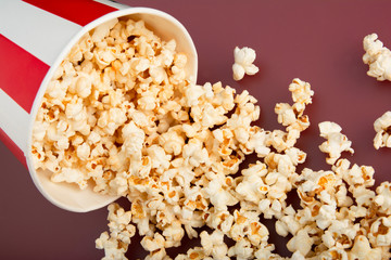 Popcorn. Paper cup of popcorn cup on a red background. Top view. Concept of entertainment.