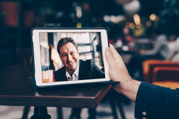 Young man having business meeting via video call in a cafe. Concept of online long distance...