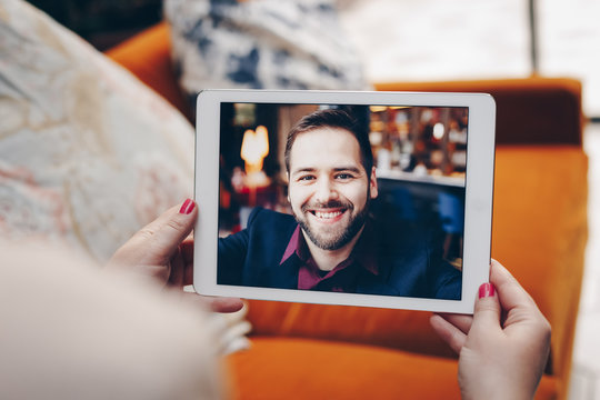 Young woman using a tablet by having a video call chat with her businessman boyfriend who is away on a business trip. Concept of keeping a long distant relationship in a career oriented world.