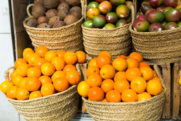 pile of juicy oranges in wicker baskets on market counter