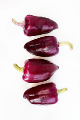 four violet peppers on a white background. vertical