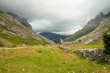 Meadows in a valley next to a traditional demolished stone building