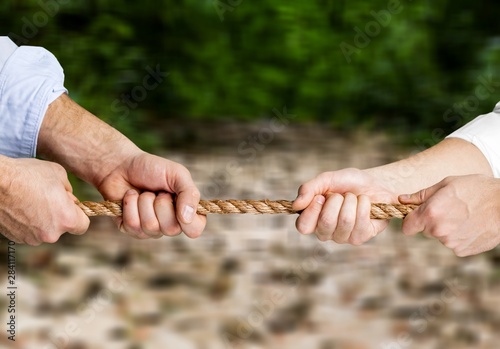 Business people pulling rope in opposite directions at office