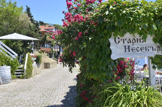 Nesabar, Bulgaria, 06/13/2017.   old nesebar plate and rose bushes on street in Nesabar near black sea, blue  sky