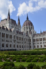 Obraz premium Budapest parliament on the background of the blue sky and green grass