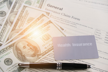 health insurance card and bank note and pen on background of general insurance claim form documents