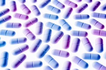 Pills in purple and blue light, arranged on a white background