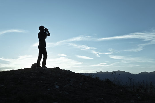 Silhouette Of A Man Looking Through Binoculars At Sunset, Wyoming, United States