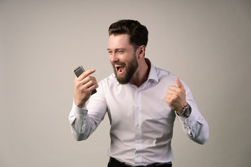 Winner concept Portrait of an excited casual man standing with raised hands and looking at camera isolated on a white background.