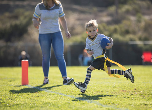 Mother watching her son score a touchdown in flag football, California, United States