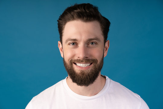 Happy young man. Portrait of handsome young man in casual shirt smiling while standing against blue background