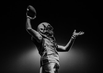 Side view of a teenage boy wearing a sports helmet and jersey holding a ball in his hand during an American football game, California, USA