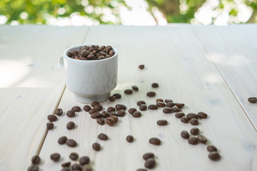 Coffee concept with cup full of coffee beans on a wooden table.