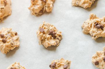 Raw chocolate chips cookie dough on wax paper in black baking tray.