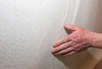 Man is installing wallpaper. Levelling of the wall. Maintenance repair works renovation in the flat. Restoration indoors.