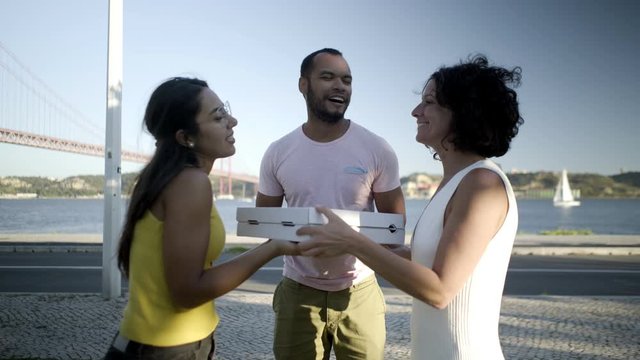 Happy young friends with pizza. Cheerful young multiethnic friends holding pizza boxes and talking outdoor. Take away food concept