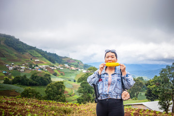 Fototapeta na wymiar Fat Asian female tourist eating corn during traveling at Mon Cham, Chiang Mai