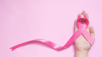 International symbol of Breast Cancer Awareness Month in October. Close up of female hand holding...