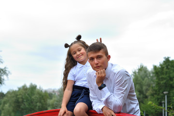 Portrait of schoolboy and first-grader girl on the background park and red bridge