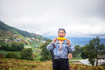 Fat Asian female tourist eating corn during traveling at Mon Cham, Chiang Mai